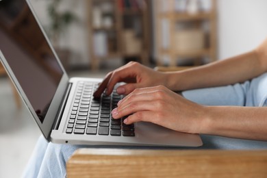 Photo of Young woman working with laptop at home, closeup