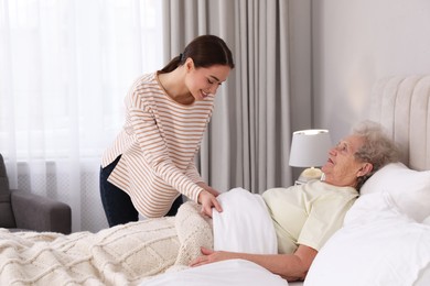 Young caregiver and senior woman in bedroom. Home health care service