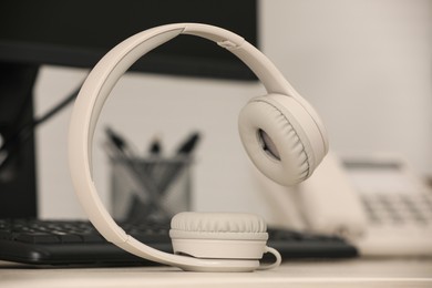 Modern headphones, desktop telephone and computer on table indoors