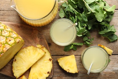 Photo of Delicious pineapple juice with fresh fruit and mint on wooden table, flat lay