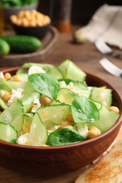 Bowl of delicious cucumber salad on wooden table, closeup