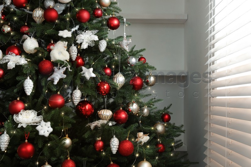 Beautifully decorated Christmas tree near window indoors