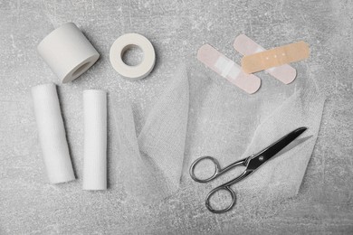 White bandage rolls and medical supplies on light grey table, flat lay
