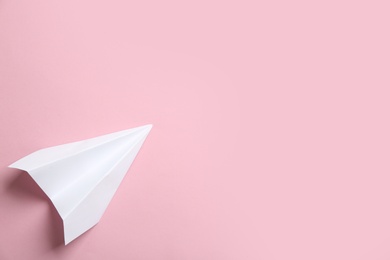 Photo of White paper plane on pink background, top view. Space for text
