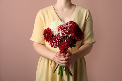 Woman with bouquet of beautiful dahlia flowers on brown background, closeup