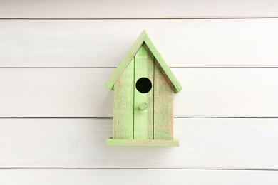 Beautiful green bird house on white wooden background