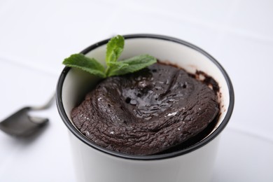 Photo of Tasty chocolate mug pie with mint on white background, closeup. Microwave cake recipe