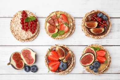 Tasty crispbreads with different toppings on white wooden table, flat lay