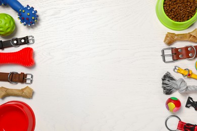 Flat lay composition with dog collars, toys and food on white wooden table. Space for text