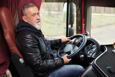 Mature driver sitting in cab of modern truck