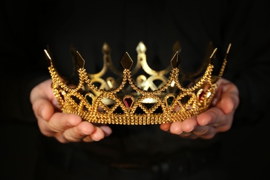 Photo of Woman holding beautiful golden crown, closeup. Fantasy item