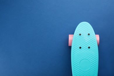 Turquoise skateboard on blue background, top view. Space for text