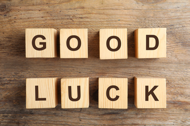 Cubes with phrase GOOD LUCK on wooden background, flat lay