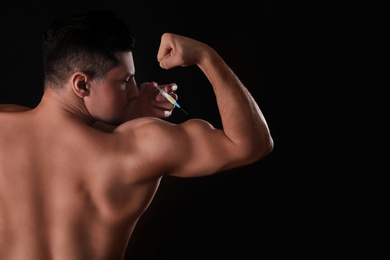 Athletic man injecting himself on black background. Doping concept