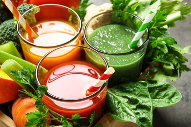 Delicious vegetable juices and fresh ingredients on table, closeup view