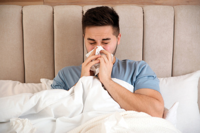 Sick young man in bed at home. Influenza virus
