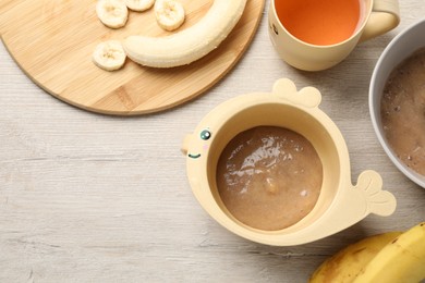Photo of Baby food. Bowls with banana puree on light wooden table, flat lay and space for text