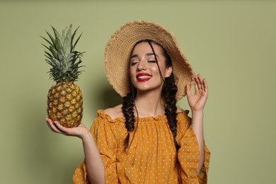 Photo of Young woman with fresh pineapple on olive background. Exotic fruit