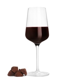 Glass of red wine and delicious chocolate candies on white background