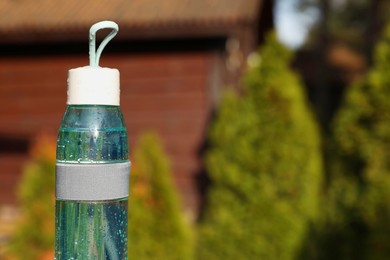 Photo of Glass bottle of fresh water outdoors on sunny day. Space for text