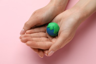 Woman holding model of planet on pink background, closeup. Earth Day