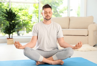 Handsome man practicing zen yoga at home