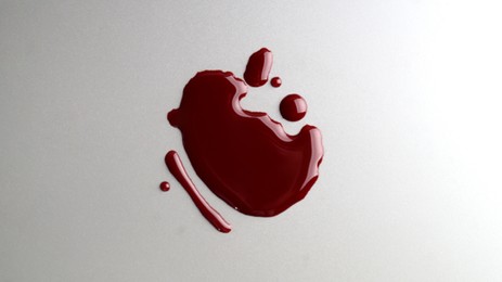 Photo of Stain and drops of blood on grey background, top view