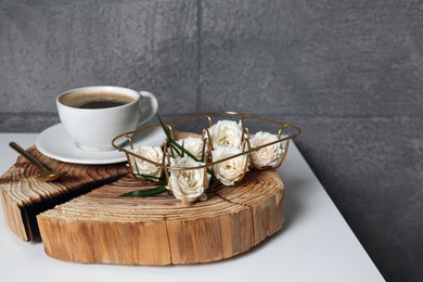 Decorative gold holder with flowers and cup of coffee on white table. Interior design