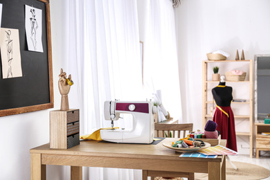 Photo of Fashion designer's workplace with sewing machine in studio. Creating new clothes