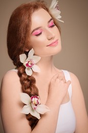 Photo of Portrait of beautiful young woman posing with lilies on beige background