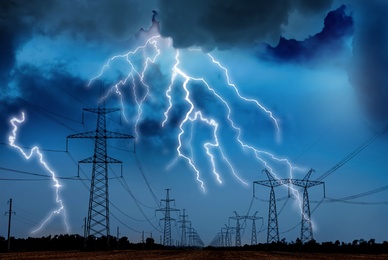 Picturesque lightning storm over field with high voltage towers