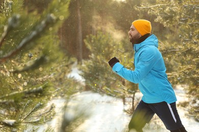Young man running in winter forest. Outdoors sports exercises