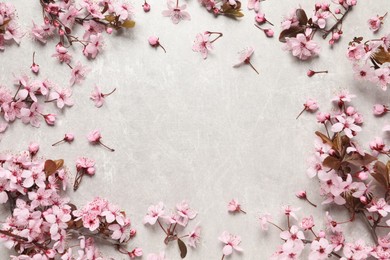 Frame of beautiful spring tree blossoms on light stone table, flat lay. Space for text