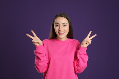 Woman showing number four with her hands on purple background