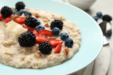 Tasty oatmeal porridge with berries and almond nuts in plate, closeup