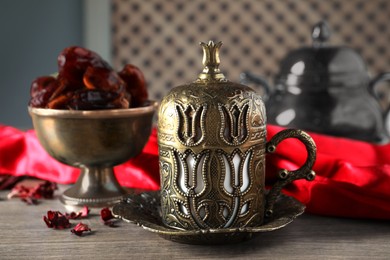 Photo of Tea and date fruits served in vintage tea set on wooden table, closeup