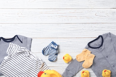 Flat lay composition with stylish baby clothes and toys on wooden background. Space for text