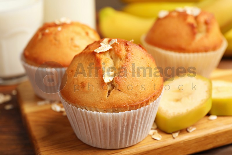Photo of Tasty muffins served with banana on wooden table, closeup