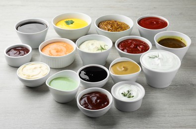 Many different sauces on white wooden table