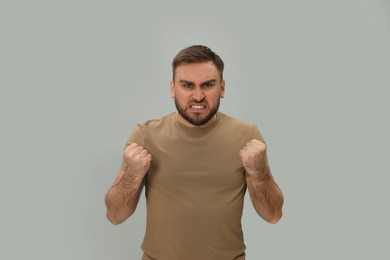 Angry young man on grey background. Hate concept