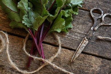 Beetroot leaves, rope and rusty scissors on wooden table, flat lay