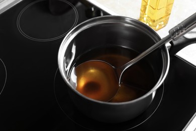 Saucepan and ladle with used cooking oil on stove
