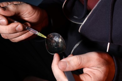 Addicted man filling syringe with drug, closeup