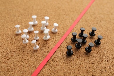 Black and white push pins divided by red strip in cork board. Racism concept