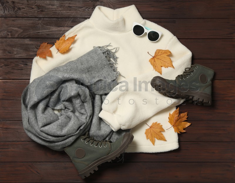Photo of Flat lay composition with sweater and dry leaves on brown wooden background. Autumn season