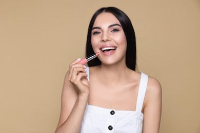 Photo of Young woman with beautiful makeup holding nude lipstick on beige background
