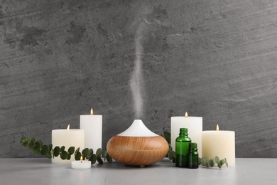 Composition with essential oils diffuser on table against grey background. Space for text