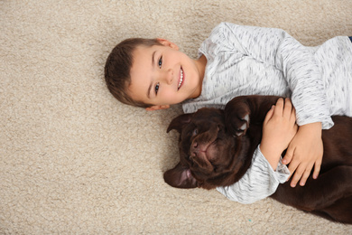 Little boy with dog lying on floor, top view