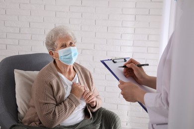 Doctor examining senior woman with protective mask at nursing home