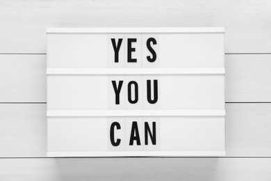 Lightbox with phrase Yes You Can on white wooden table, top view. Motivational quote